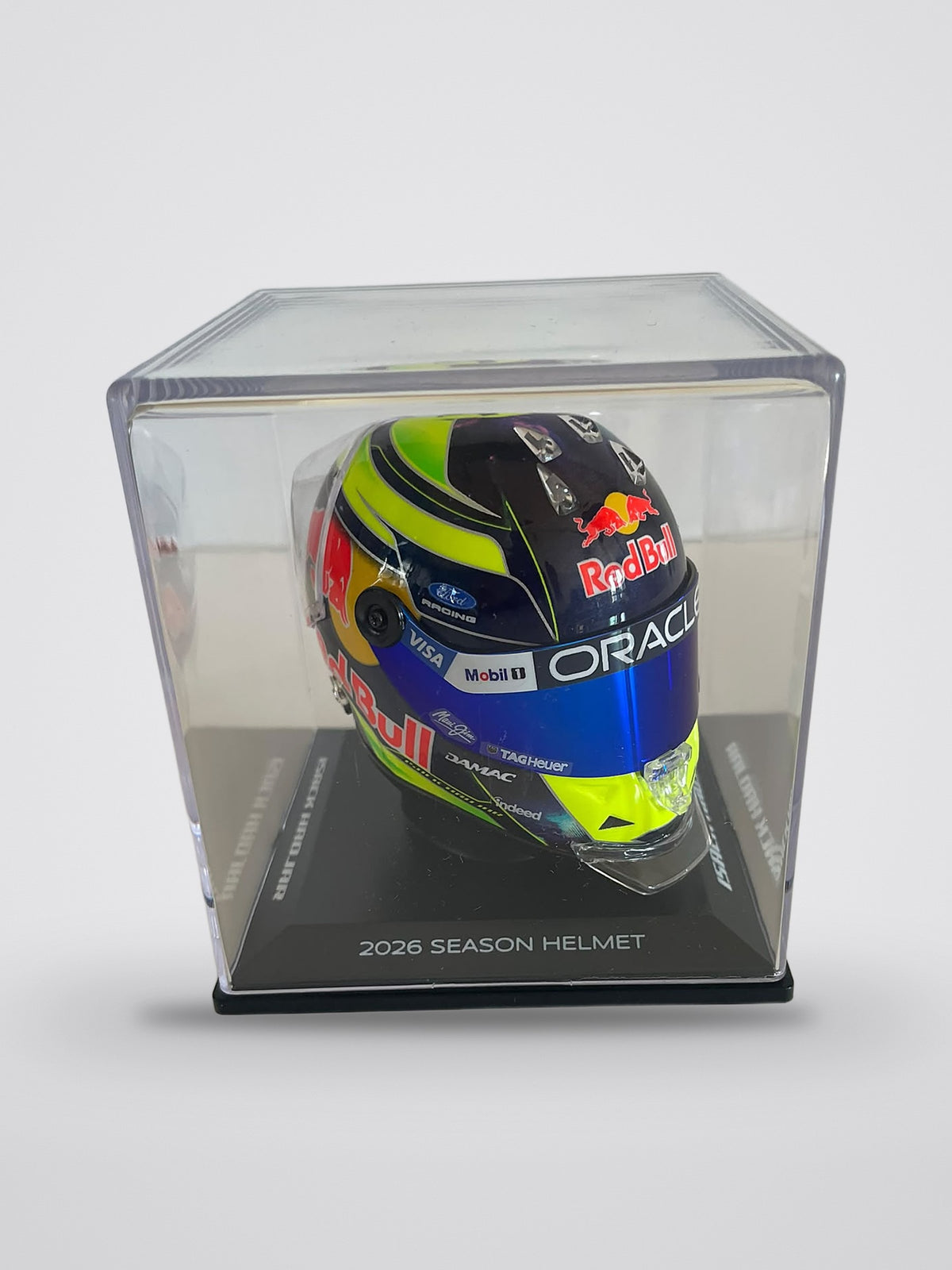 Isack Hadjar 2026 season mini helmet, 1:4 scale, in its clear acrylic display case, base marked 2026 Season Helmet